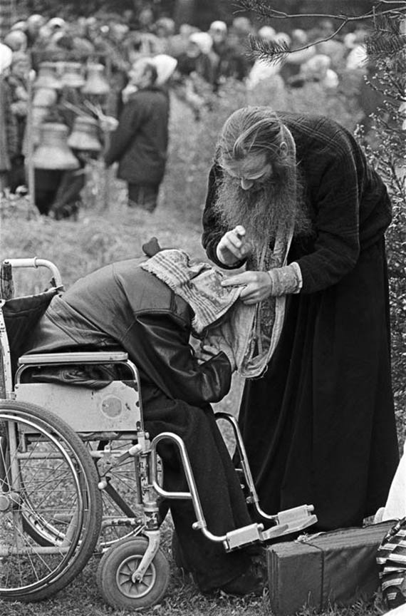 Фото Сергея Склярова. Человек в инвалидной коляске и священник 