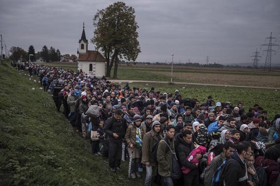 Migrants walk past the temple as they are escorted by Slovenian riot police to the registration camp outside Dobova, Slovenia, Thursday October, 22, 2015. The small Balkan nations on the path of the human migration through Europe are seeing record numbers of asylum-seekers cross their borders, and are overwhelmed in their ability to manage the human flow. Despite hopes that plummeting temperatures and treacherous seas would finally slow the tide of refugees flowing into the heart of Europe, fresh fighting in Syria and growing fears of border closings are driving more migrants to undertake the treacherous trek.