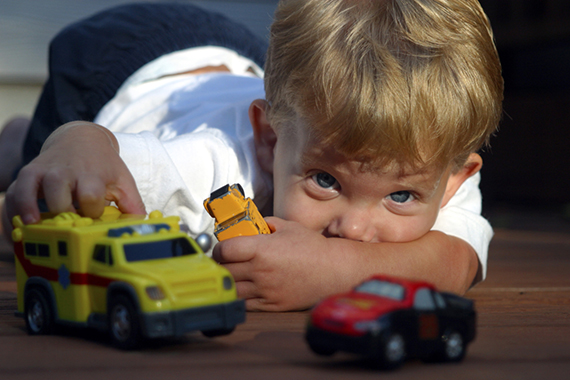 Caucasian Boy Playing With Toy Trucks On The Floor