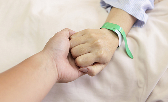 husband grip his wife's hand before surgery