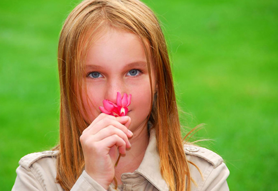Девочка нюхает красный цветок