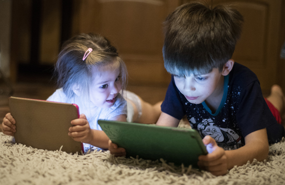 Мальчик и девочка смотрят в планшеты