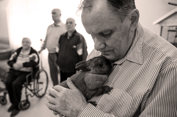 Пожилой мужчина на фоне других больных держит кролика