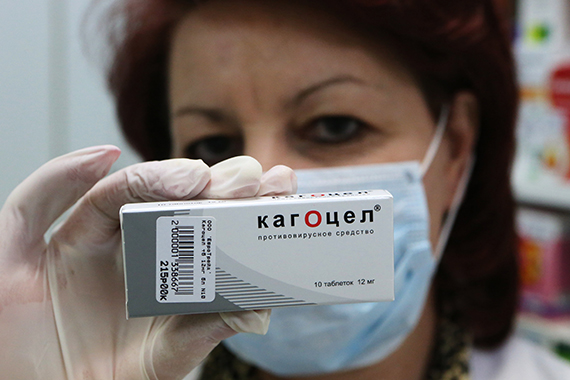 Фармацевт демонстрирует упаковку с лекарственным препаратом "Кагоцел"