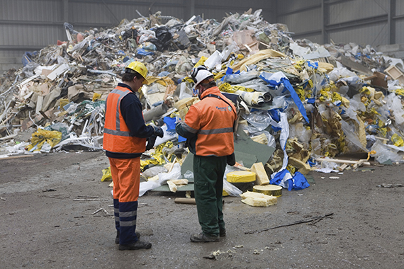 Работники мусороперерабатывающего завода на фоне горы мусора 