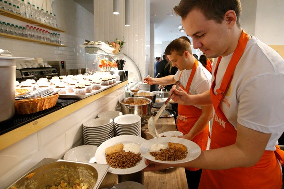 Добровольцы накладывают еду в благотворительном кафе "Добродомик"