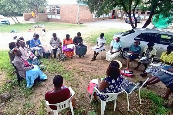 Африканцы сидят в кругу, слушают женщину и делают заметки 