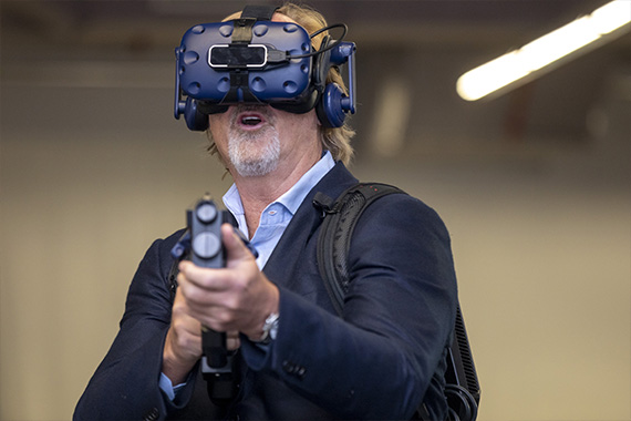 Мужчина в шлеме виртуальной реальности с VR оружием