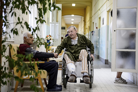 Мужчина в инвалидной коляске держится за руки с сидящим в кресле пациентом