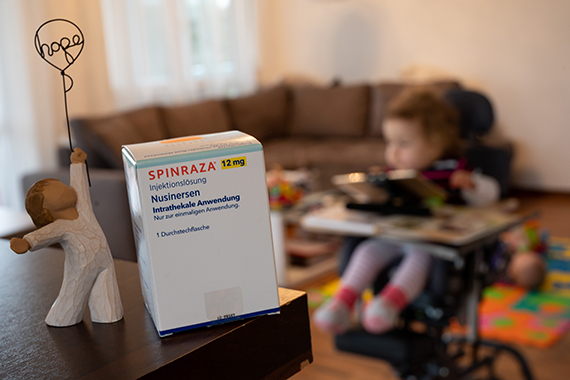 Упаковка препарата "Спинраза" на фоне комнаты с маленьким ребенком
