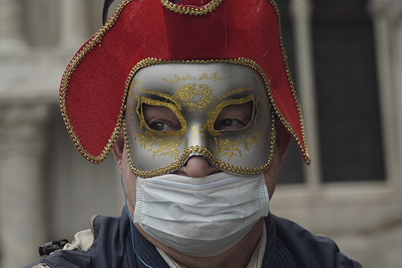 Мужчина в маскарадной и медицинской масках в Венеции 