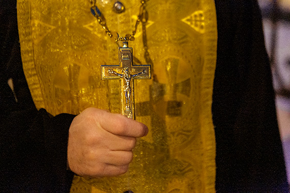 Рука священника держит крест