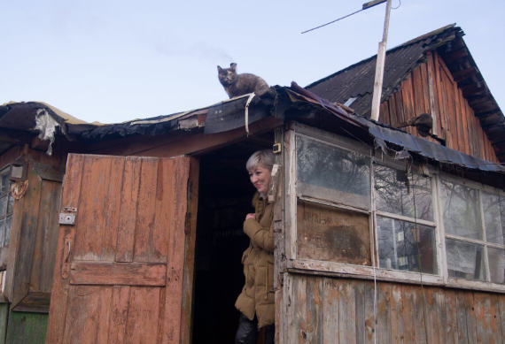 Женщина в дверном проеме старого деревенского домика