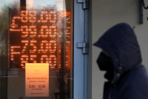 Человек в маске и капюшоне на фоне электронного табло курса валют 