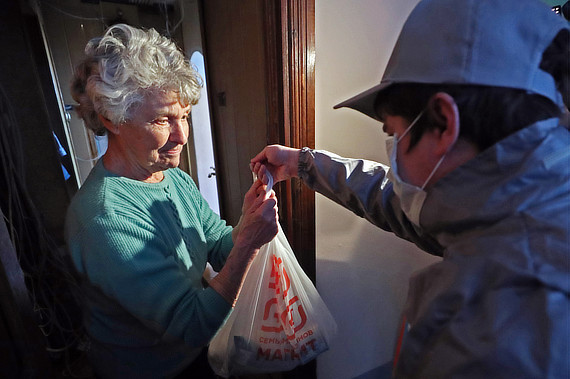 Волонтер выдает пакет с продуктами бабушке