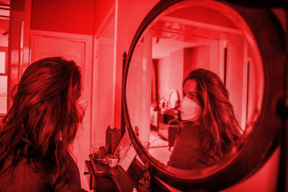 Девушка в маске смотрит в зеркало