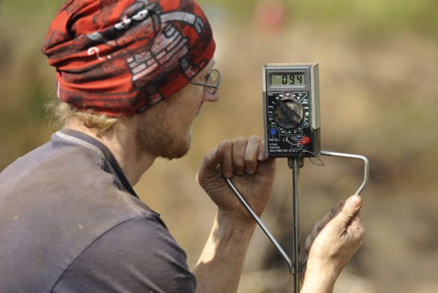Мужчина измеряет температуру торфяного слоя с помощью специального прибора