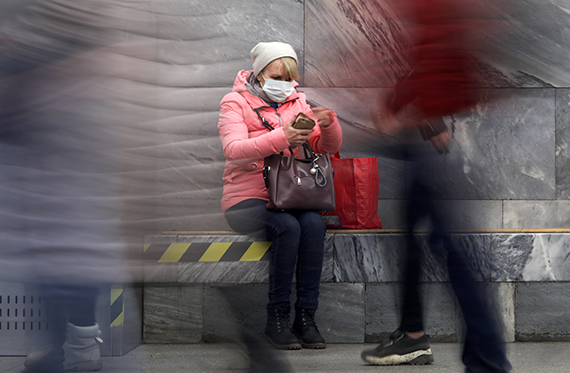 Женщина в медицинской маске сидит в вестибюле метро