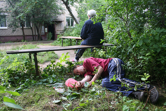 Женщина сидит на скамейке в саду, мужчина лежит у скамейки