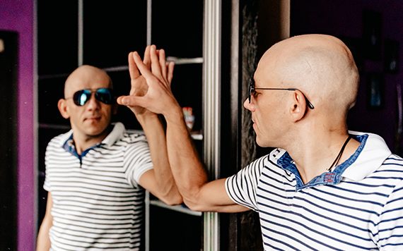 Мужчина в солнцезащитных очках положил ладонь на зеркало