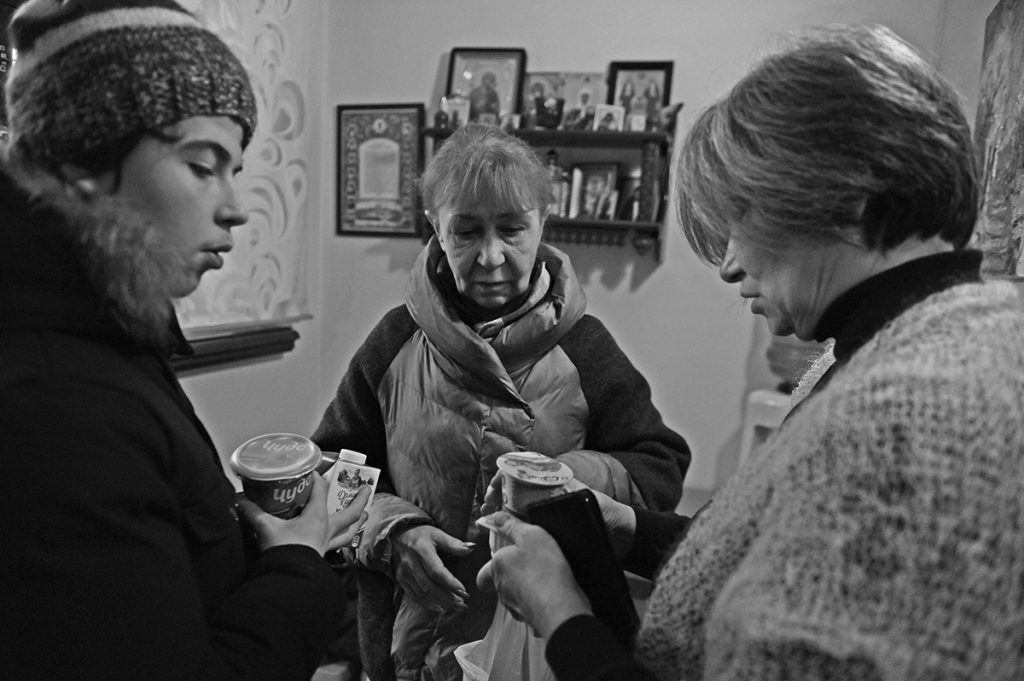 Две пожилые женщины и парень с продуктами в руках беседуют