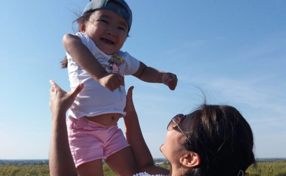 Мама подбрасывает вверх маленькую дочку