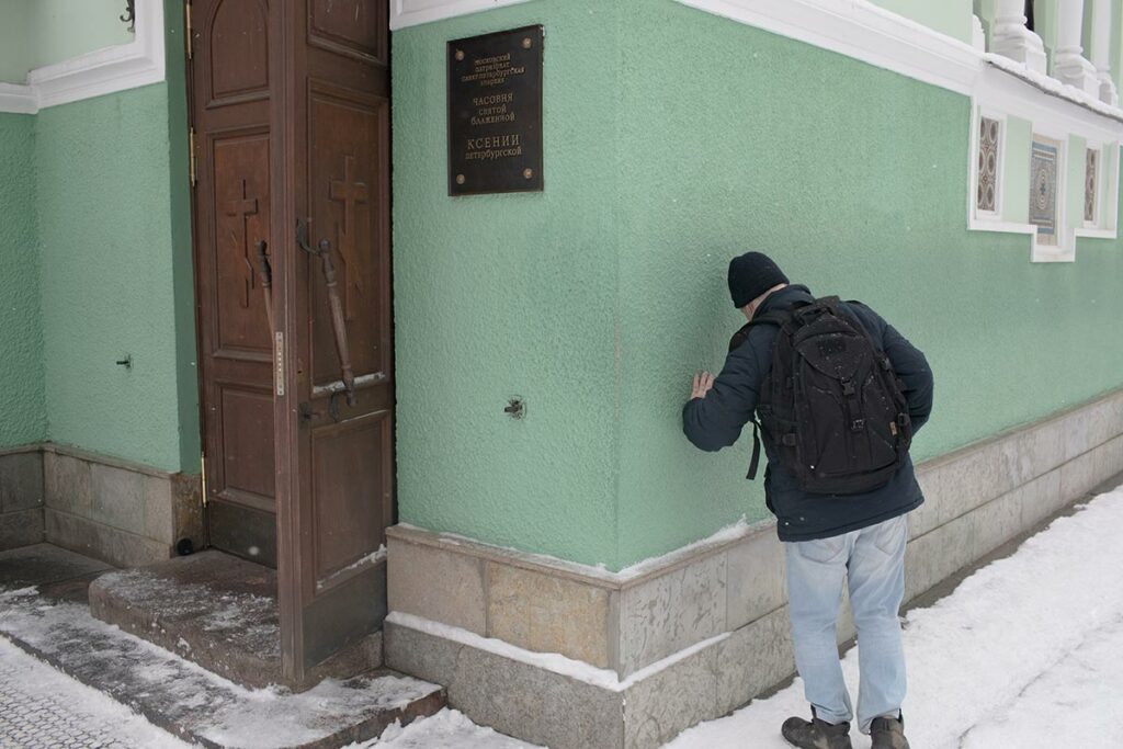 Мужчина, прислонившийся к стене часовни святой блаженной Ксении Петербургской