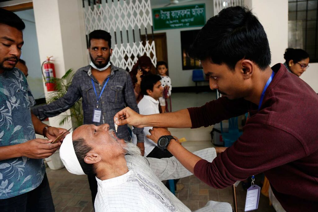 Медицинские работники вакцинируют жителей города Дакки. На первом плане вакцинируется пожилой мужчина 