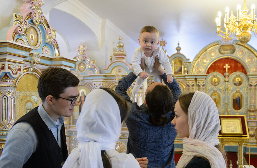 Крестные и младенец с родителями в церкви перед началом крещения