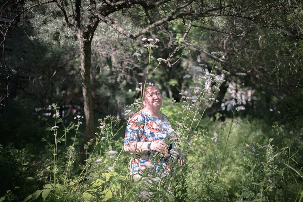 Ирина Анатольевна в саду, ее окружает растение – валериана лекарственная