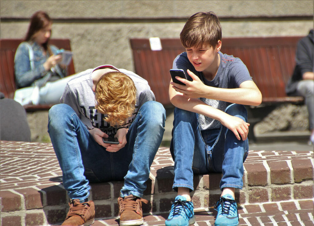 Подростки юноши смотрят в телефоны 