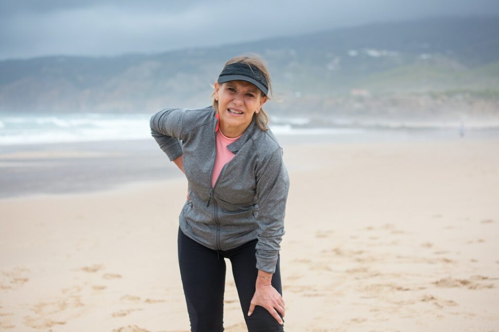 Женщина, которую скрутила боль на пляже во время пробежки