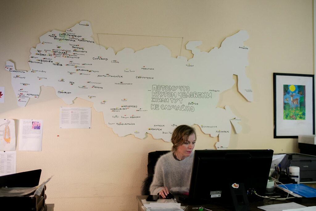 Юлия Корсунская за рабочим столом, на стене карта