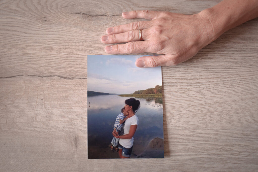 Рука Анны и фотография, где она на берегу реки держит сына на руках