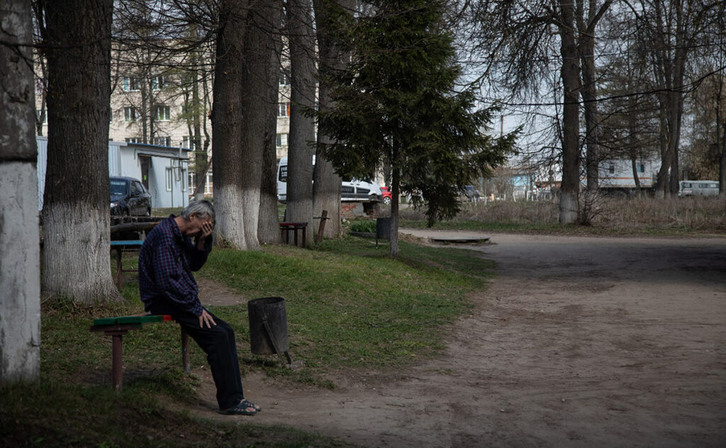 Мужчина сидит на лавочке около дороги