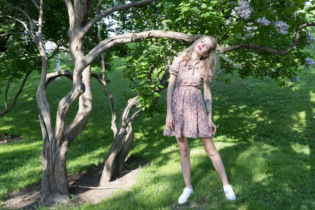 Екатерина в легком летнем платье у цветущей сирени