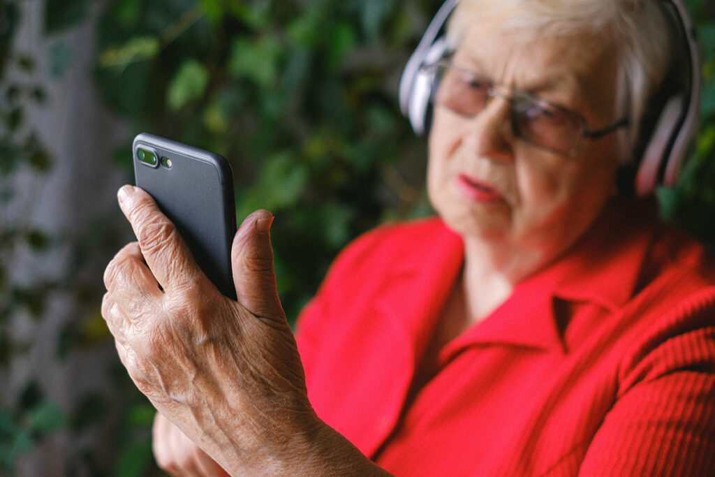 Женщина в красной блузке слушает музыку в наушниках с телефона