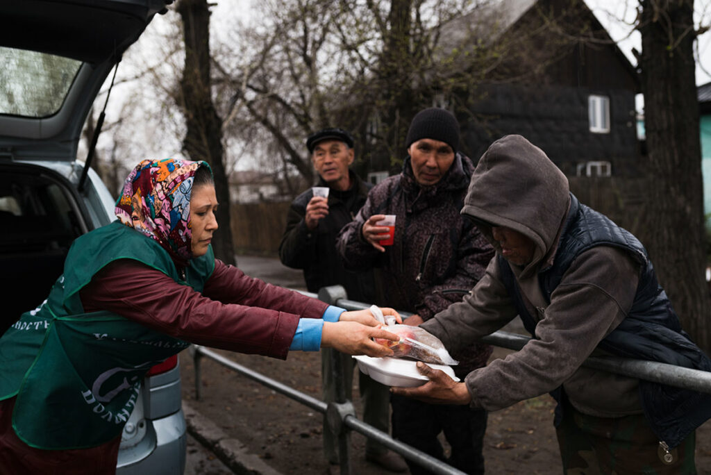 Кормление бездомных. Волонтер раздает еду