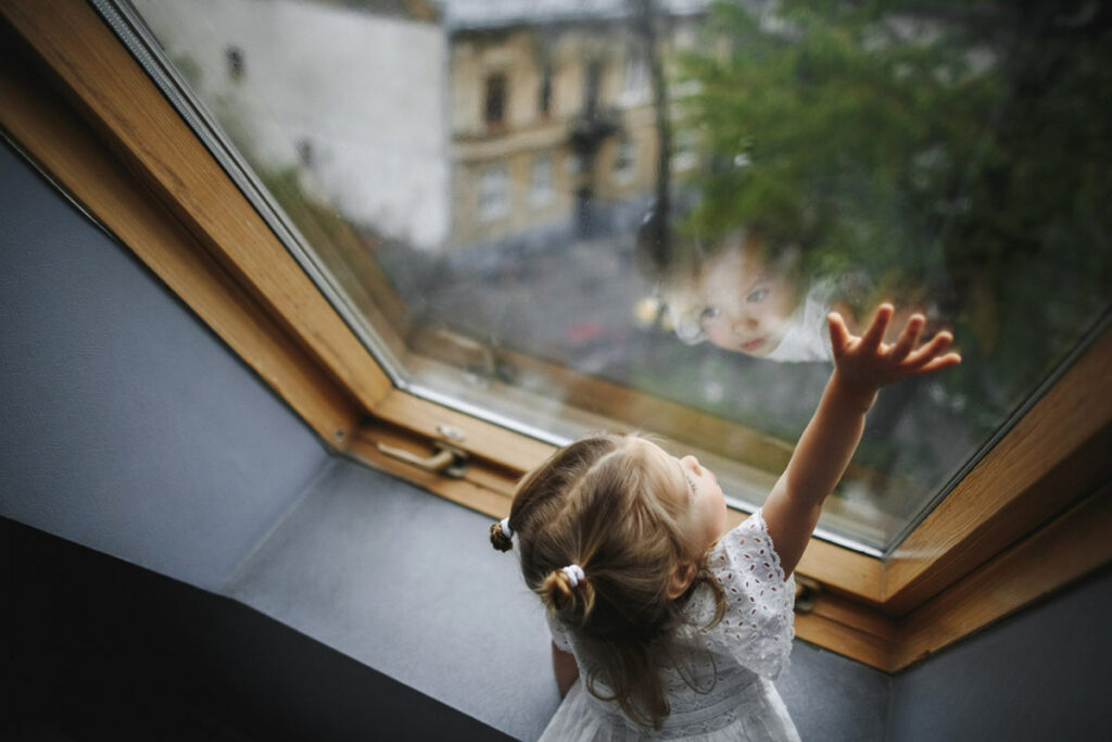 Маленькая девочка у окна на подоконнике