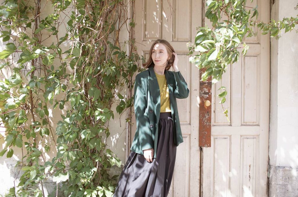 Полина Гришанова на фоне двери с вьющимися растениями
