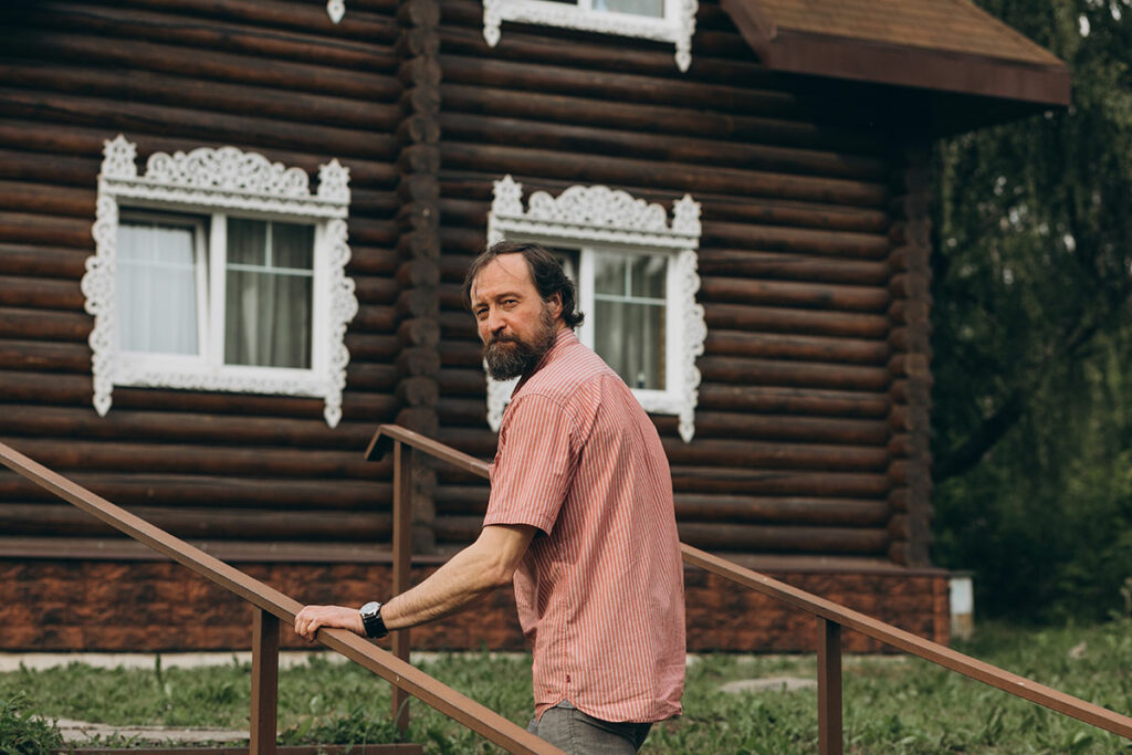 Александр на фоне деревянного дома