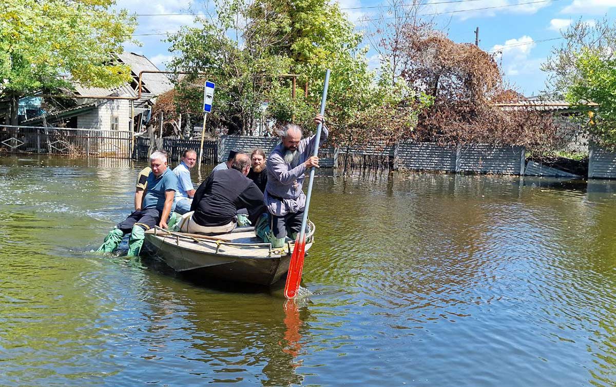 Представители Синодального отдела по благотворительности плывут на лодке по затопленной улице