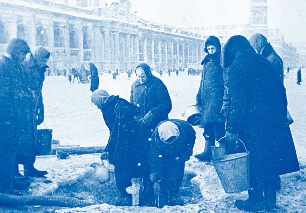 Жители блокадного Ленинграда набирают воду, появившуюся после артобстрела в пробоинах в асфальте на Невском проспекте. Декабрь 1941 года