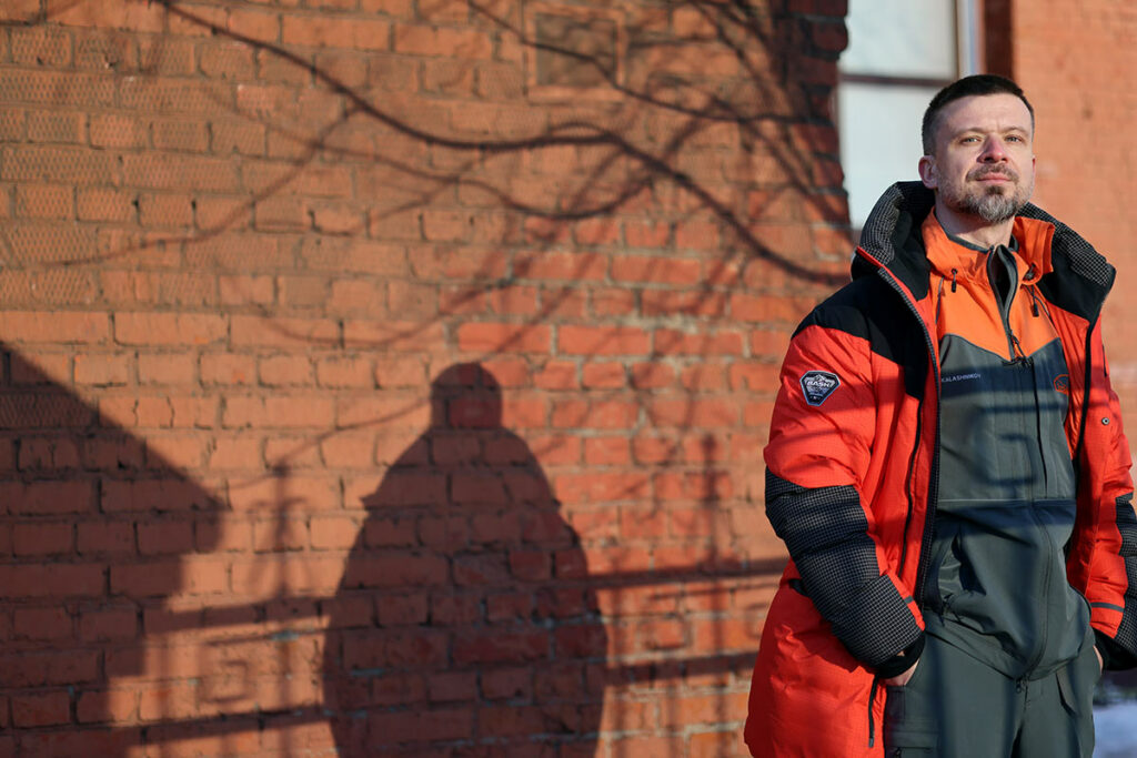 Григорий Сергеев на улице на фоне красной кирпичной стены