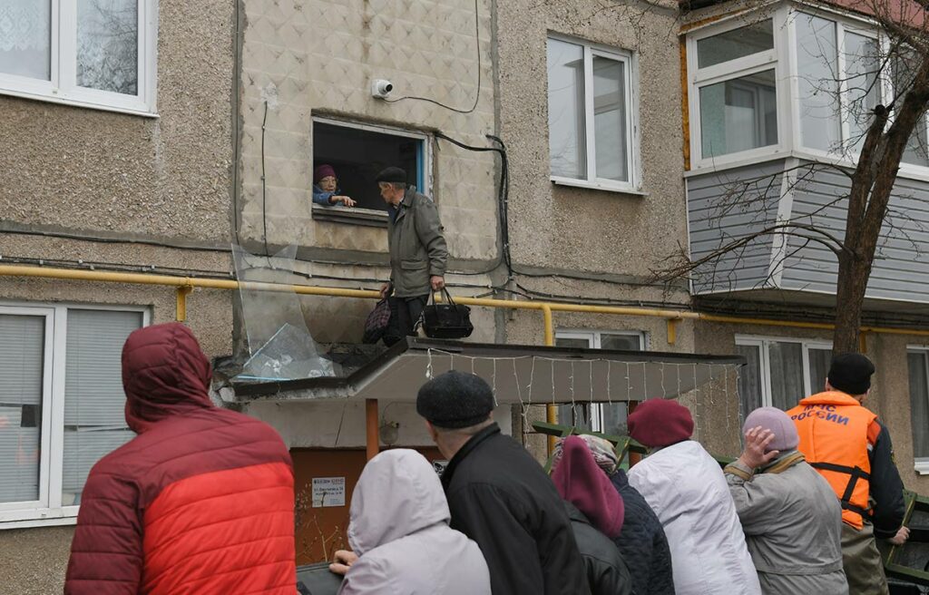 Эвакуация жителей через окно над козырьком подъезда, оттуда сотрудники МЧС помогают им спуститься в лодку