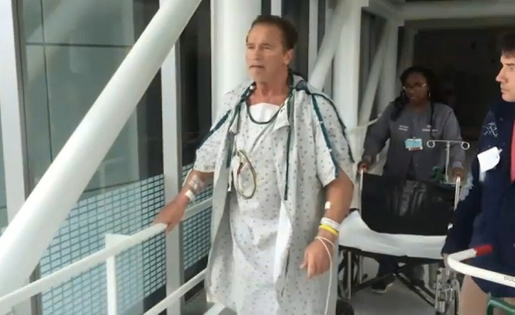 Арнольд Шварценеггер идет по больничному коридору после операции