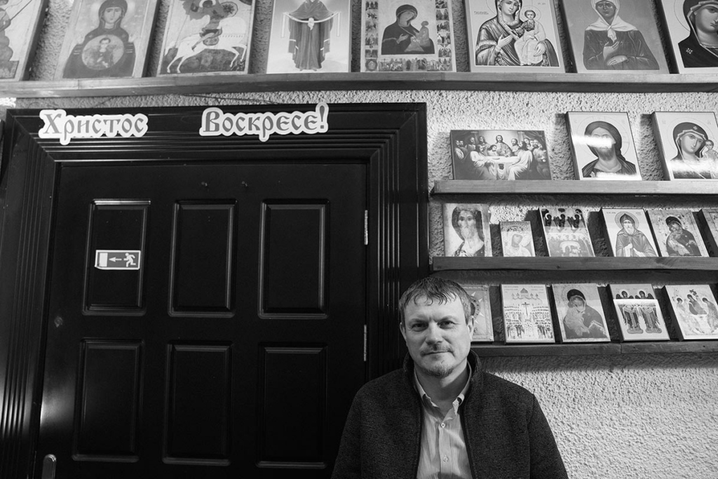 Черно-белый портрет мужчины средних лет на фоне икон