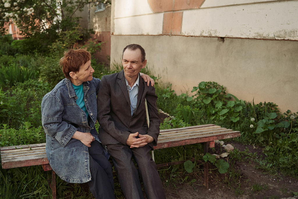 Елена с мужем на скамейке у дома 