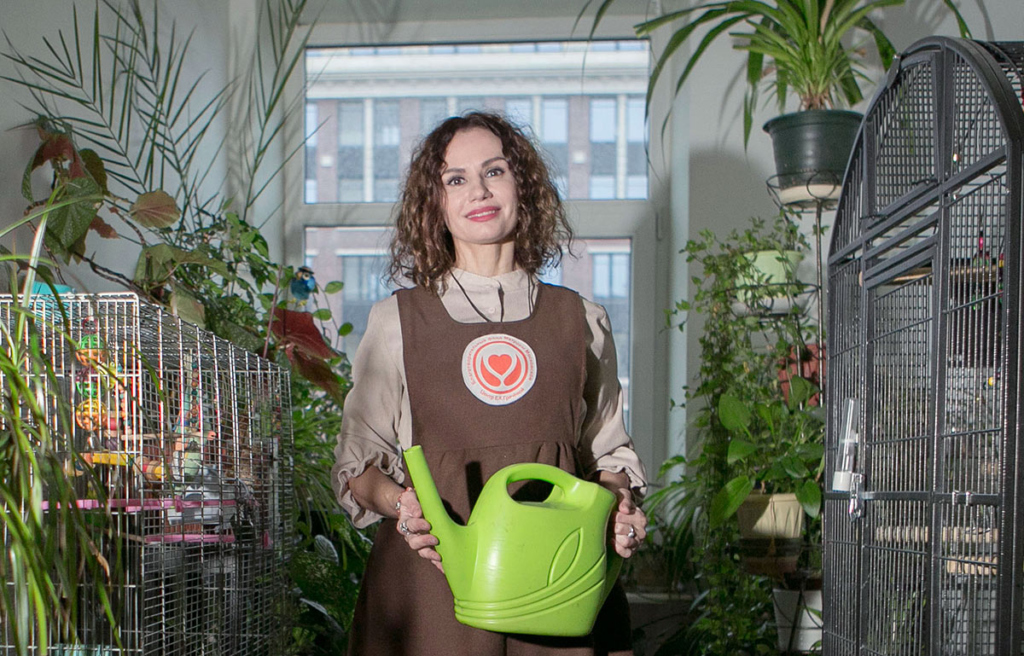 Молодая женщина с лейкой в оранжерее