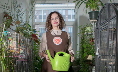 Молодая женщина с лейкой в оранжерее